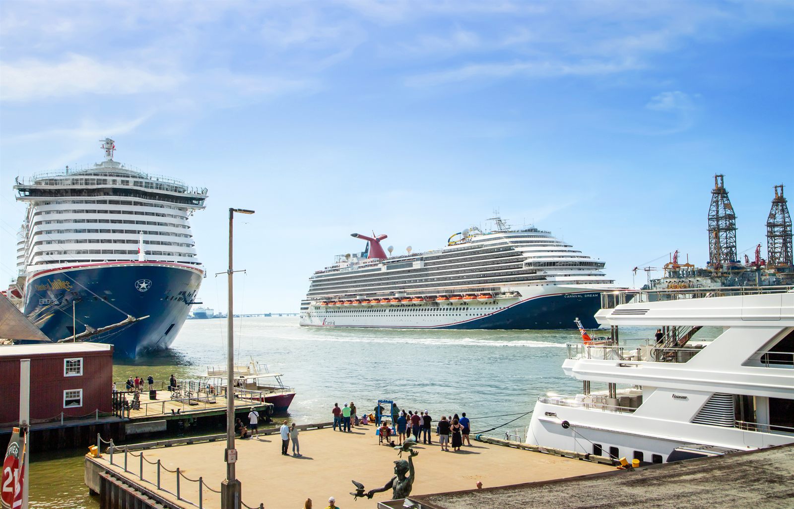 Passengers walking along a pier beside large cruise ships in port